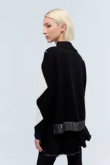 Sweater de punto negro con cuello alto y diseño de jacquard con rombos blancos y bordado de flores fucsia.