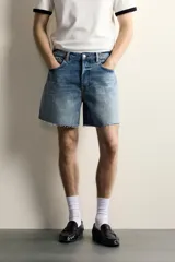 Shorts de denim de algodón con ajuste regular, diseño de cinco bolsillos y efecto lavado. Presenta cierre frontal con cremallera y botón, con el bajo acabado en corte irregular.