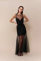 Vestido midi negro con cuerpo bordado en lentejuelas y canutillos, escote redondo y falda con superposición de tul transparente. Presenta espalda descubierta y cierre invisible.
