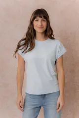 Remera básica color celeste, de corte relajado, cuello redondo y mangas cortas con hombro caído y dobladillo.