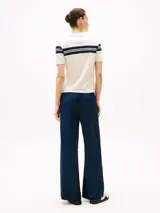 Chomba blanca de piqué de algodón elástico con rayas horizontales azul marino en cuello y mangas, corte slim, cuello de chomba con tapeta de seis botones y logo de Tommy Hilfiger bordado en la manga.