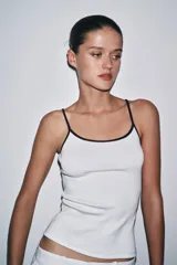 Camiseta de tirantes finos, corte ajustado al cuerpo y escote redondo. El cuerpo es de tejido azul marino jaspeado y el ribete del escote y los tirantes son de color rojo.