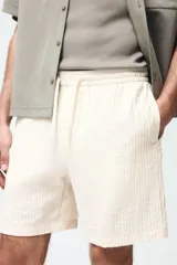 Short texturizado de mezcla de viscosa, color beige, con cintura elástica con cordón de ajuste y bolsillos laterales.