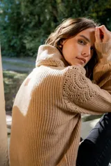 Sweater de punto color gris claro, con cuello amplio tipo solapa y detalles de tejido crochet en los hombros y mangas. Presenta mangas largas con puños ajustados y diseño de corte holgado.