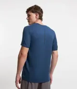 Remera deportiva de hombre con tecnología dry fit, cuello redondo y manga corta. Presenta un diseño liso en color beige con una pequeña etiqueta decorativa en el dobladillo.