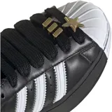 Championes adidas Superstar de plataforma, color negro con las icónicas tres tiras laterales en blanco y puntera de goma blanca. Presentan un diseño clásico con cordones negros y detalle metálico en la parte superior.