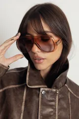 Lentes de sol estilo aviador con armazón de policarbonato en tono ámbar translúcido y cristales degradados en tonos marrones. Cuentan con protección UV400.