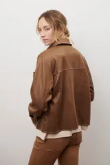Chaqueta color camel con cuello camisero, cierre frontal con botones dorados, dos bolsillos de parche en el pecho y costuras decorativas en contraste.