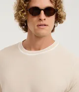 Remera regular de manga corta y cuello redondo color negro, con diseño texturizado y detalles de rayas contrastantes en cuello y puños.