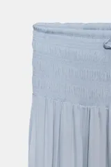 Falda larga color crudo, de tiro alto con cintura elástica tipo nido de abeja y cordón ajustable.