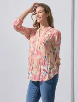 Blusa de gasa estampada con flores en tonos rosa, amarillo y azul. Tiene cuello a la base, escote en V y botones. La delantera tiene detalle plisado y las mangas son 3/4 regulables con presilla y botón.