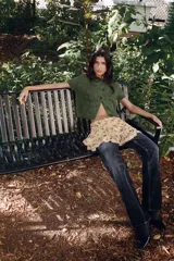 Chaqueta de punto de textura peluda en color verde, con cuello redondo, manga corta y cierre frontal con botones a tono.