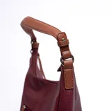 Cartera tipo hobo color bordó, con correa de hombro marrón y cierre superior con cremallera.