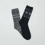 Set de dos pares de medias largas, uno gris con diseño geométrico en blanco y otro negro con diseño de copos de nieve en blanco.