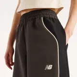 Pantalón de jogging New Balance modelo Trackside, color gris oscuro, con cintura elástica, bolsillos laterales y líneas ribeteadas en color blanco en los laterales. Presenta el logo de la marca bordado en el muslo izquierdo.