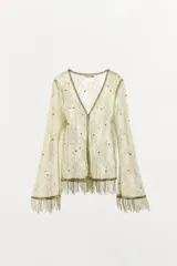 Chaqueta de encaje color verde militar con escote en V, mangas largas acampanadas y flecos en el bajo. Cuenta con detalles de abalorios y cuentas bordadas a tono.