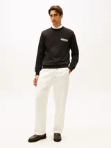 Buzo de cuello redondo Tommy Hilfiger de color negro, confeccionado en tejido interlock técnico de algodón y poliéster. Presenta corte regular, puños y bajo de punto canalé, con un parche bordado del logo de la marca en el pecho y la bandera distintiva bordada en el puño.
