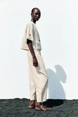 Chaqueta corta de escote en pico con cierre frontal de un botón. Presenta mangas cortas con detalle de vuelta, trabilla y botón, además de falsos bolsillos delanteros con solapa.