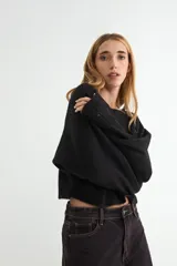 Sweater de punto negro, de corte holgado y diseño cropped, con cuello redondo y mangas largas.