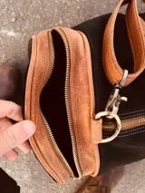 Bolso de viaje grande de cuero vacuno color negro con detalles en marrón. Tiene herrajes metálicos, gran superficie interna, asa de mano y correa para el hombro.