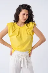 Remera amarilla con hombreras y pliegues en el frente.
