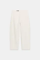Pantalón de tiro medio en color crudo, con diseño de corte recto y trabillas en la cintura. Presenta cierre frontal con cremallera y gancho metálico.