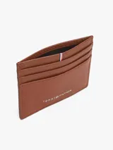 Tarjetero de piel con acabado granulado, diseño minimalista con múltiples ranuras exteriores para tarjetas, cinta distintiva de la marca en la parte superior y logo metálico en relieve en la parte frontal.