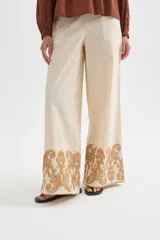 Pantalon ancho de algodón en color beige con detalle de bordado decorativo en el ruedo.