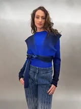 Buzo de punto confeccionado en 100% lana merino con efecto degradé en tonos azules. Presenta un diseño versátil con lazos largos que nacen de la cintura alta para anudar de diferentes formas, mangas entalladas con ojal para el pulgar y cuello redondo.