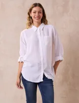 Camisa blanca de lino con cuello con solapa, manga larga regulable con presilla y botón, y abertura central con botones.
