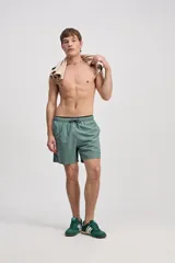 Short de baño verde militar de largo corto, con cintura elástica y cordón ajustable. Cuenta con bolsillos laterales y uno trasero.