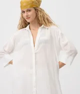Salida de playa tipo túnica camisera blanca, con mangas 3/4, cuello camisero y cierre frontal con botones. Confeccionada en algodón certificado BCI.