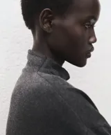 Chaleco de punto en color gris oscuro, con cuello alto y diseño sin mangas. Presenta un corte recto y tejido de textura suave.