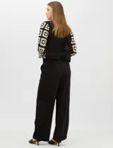 Cardigan abierto de tejido de punto calado con diseño geométrico bicolor en mangas y paneles frontales, y espalda en tono sólido. Presenta silueta recta, frente abierto sin cierre y terminaciones con vivos reforzados en escote, puños y ruedo.