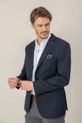 Saco de vestir entallado en color azul marino, confeccionado en gabardina de lana. Presenta solapas clásicas, cierre frontal de un botón, bolsillos laterales y un bolsillo en el pecho con pañuelo estampado.