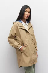 Piloto verde militar de manga larga con capucha y forro de color amarillo. Cuenta con dos bolsillos laterales con solapa, cordones ajustables, elástico en los puños, cierre y botones metálicos.