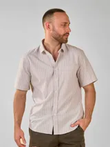 Camisa de manga corta con cuello camisero y botones frontales. El tejido es de color crema con un patrón de cuadros pequeños en negro y marrón.