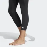 Calza deportiva Adidas Techfit de corte 3/4, color negro. Presenta cintura elástica con logo y tecnología Techfit para compresión muscular, además de inserciones de malla para mayor ventilación y tecnología Climacool que gestiona la humedad.