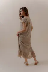 Vestido largo tejido color beige, con diseño en bloques de rombos, escote en V y flecos en el ruedo.