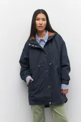 Piloto azul marino de manga larga con capucha y forro color marrón. Tiene dos bolsillos laterales con solapa, cordones ajustables, elástico en los puños, cierre y botones metálicos.