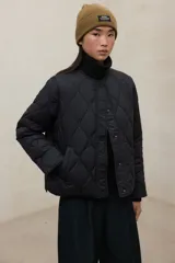 Campera acolchada con diseño de costuras onduladas tipo onion, color negro. Confeccionada en poliéster reciclado, cuenta con cuello redondo, cierre frontal con botones a presión y bolsillos laterales. Es una prenda repelente al agua.