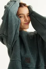 Buzo oversize de corte unisex, color rojo con efecto desgastado (acid wash), confeccionado en algodón con interior de polar. Presenta costuras frontales decorativas, hombros caídos, mangas largas con puños elastizados, rib en el cuello y el ruedo, y un pequeño logo bordado en el pecho.