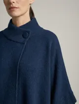 Capa tejida color fucsia, con cuello alto abotonado y mangas cortas estilo japonesa. Tejido de punto grueso.