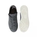Championes Adidas modelo Stan Smith Nuud, color gris con acabado en gamuza. Presentan un diseño minimalista con suela de goma en color crema y detalles internos en tono rojizo.