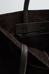 Bolso tipo shopper de diseño minimalista, confeccionado en piel con acabado de serraje. Cuenta con dos asas largas de mano y un compartimento principal espacioso con un bolsillo interior con cierre.