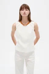 Musculosa blanca sin mangas de viscosa, con ajuste al cuerpo, cuello a la base y detalles de vivos.