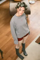 Buzo color naranja con cuello redondo, manga larga y un pequeño corazón bordado en el frente. La espalda presenta un bordado con el significado de "Munay" y un poema. Confeccionado en rústico de algodón.