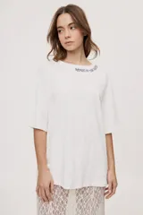 Remera de manga corta y cuello redondo, de corte oversized en color marrón, con texto bordado o estampado a lo largo del escote en el hombro izquierdo.