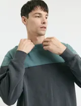 Sweater de tejido circular con diseño color block, combinando una franja superior en color verde y el resto de la prenda en gris oscuro. Presenta cuello redondo y puños en tejido canalé.