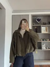 Campera tipo bomber de gamuza en color verde militar, con cierre frontal, cuello camisero y diseño holgado.